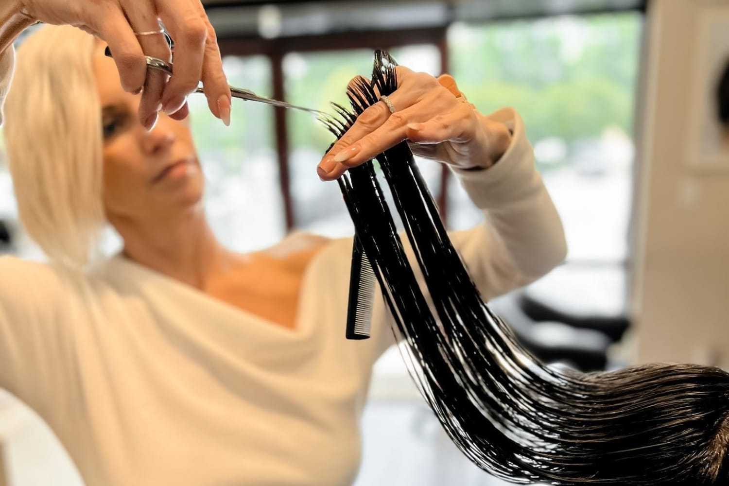Hairdresser cutting wet hair with scissors in a salon.