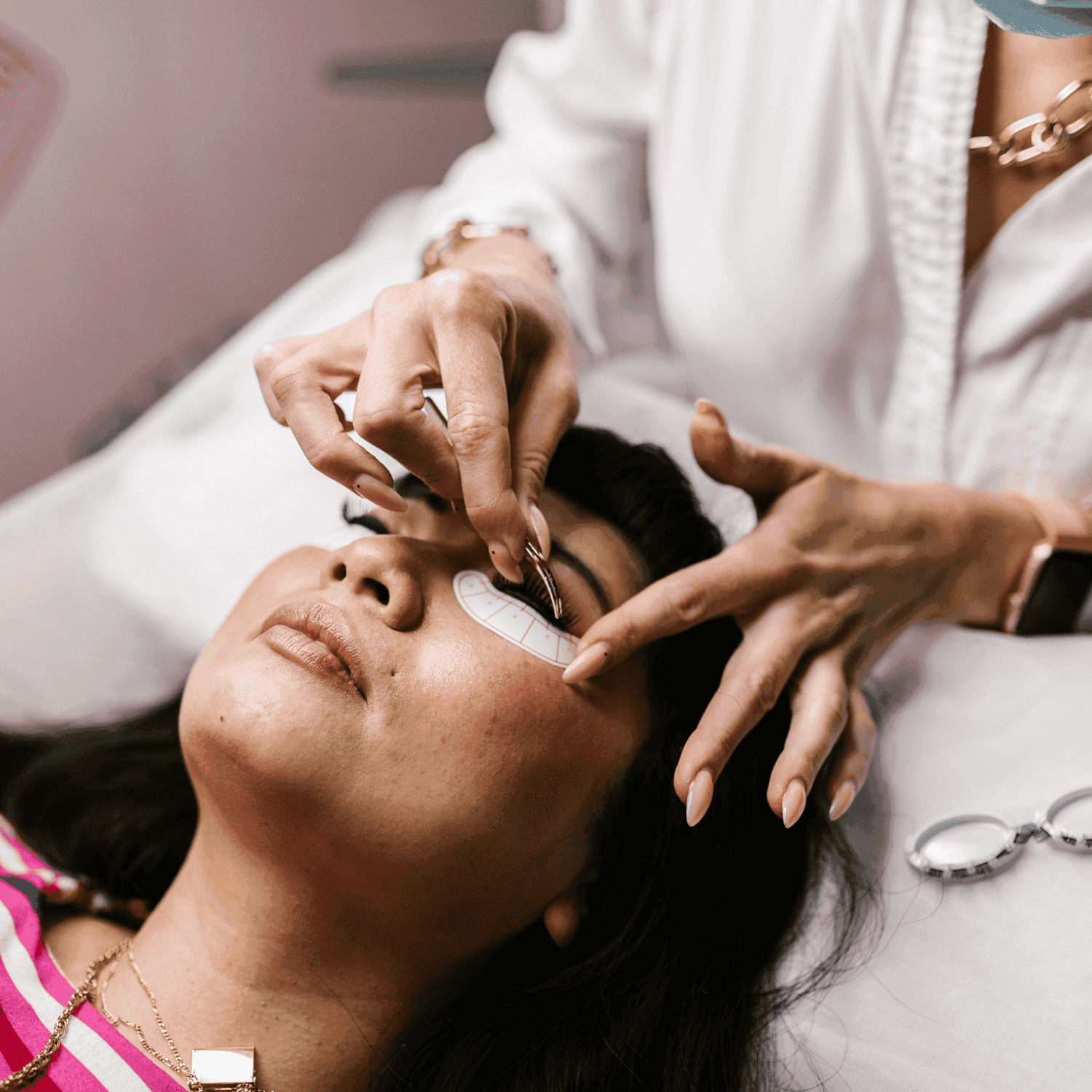 Woman receiving eyelash extension treatment in a beauty salon.